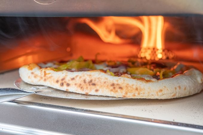 Cooked Pizza Coming out of Oven 